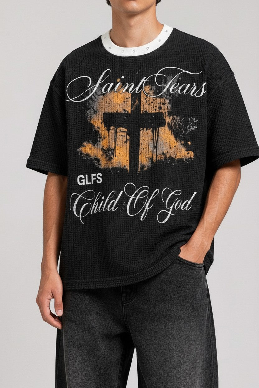 PAKSHI black waffle knit t-shirt featuring a Saint Tears graphic print, cross design, and a white studded collar.