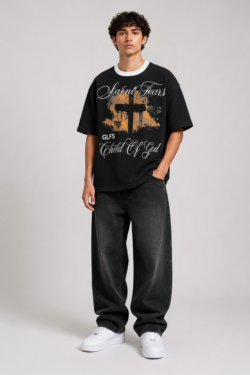 PAKSHI black waffle knit t-shirt with a graphic cross print and white crew neck, worn by a male model with jeans.