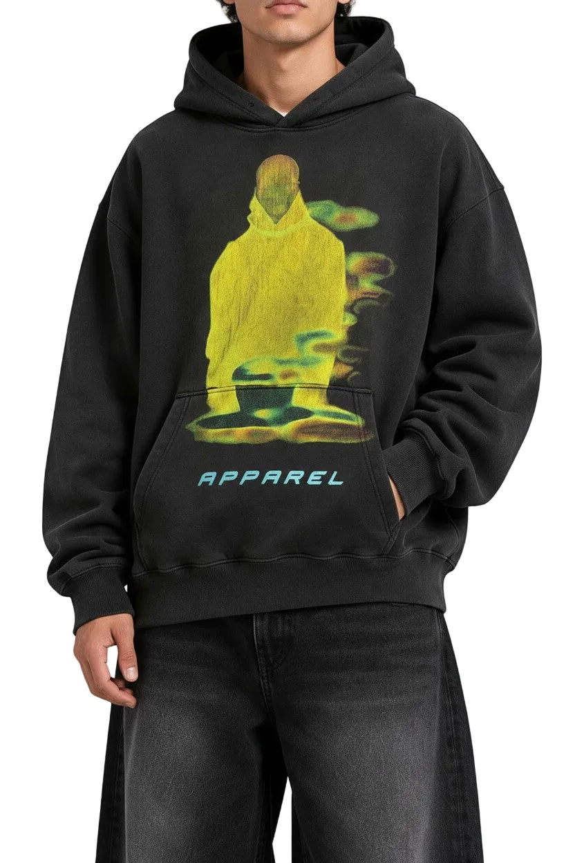 Model wearing a PAKSHI oversized black heavyweight hoodie with a yellow graphic print and blue apparel text