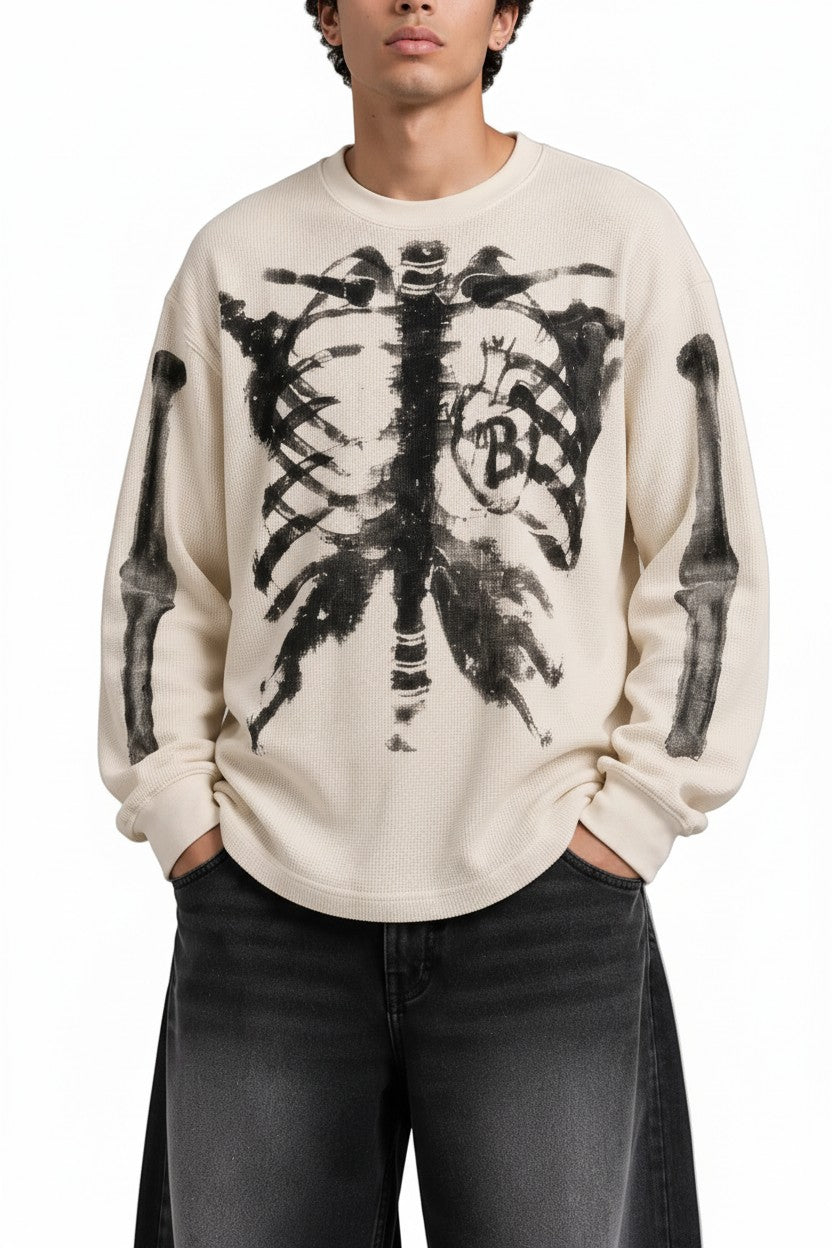 PAKSHI cream waffle knit long-sleeve t-shirt featuring a black distressed skeleton rib cage graphic on the front.